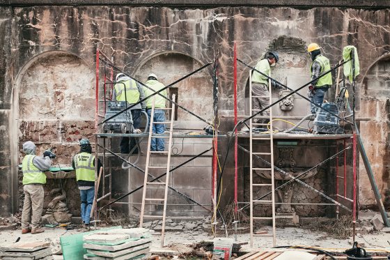 a group of construction workers cleaning a dirty stone wall