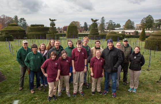 a group of children smiling for the camera with topiaries in the background