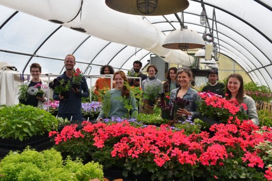 a group of people standing behind a table of poinsettias smiling at the camera