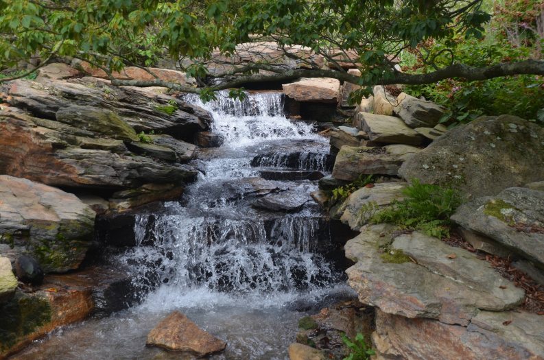 A waterfall rushes over a bed of rocs and large stones