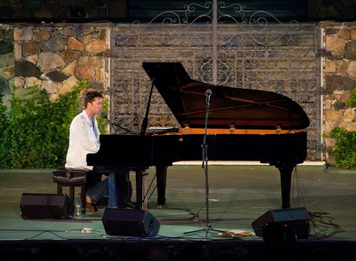 Man sits at a piano on a stage