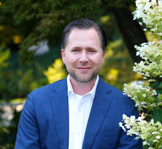 A person in a blue suit jacket and white shirt looking at the camera. 