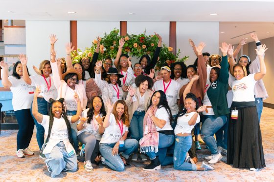 A group of people kneeling and standing waving and smiling at the camera. 