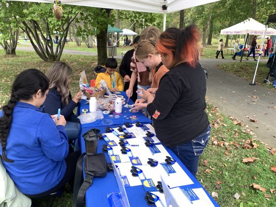 People at an outdoor table making Christmas ornamments. 