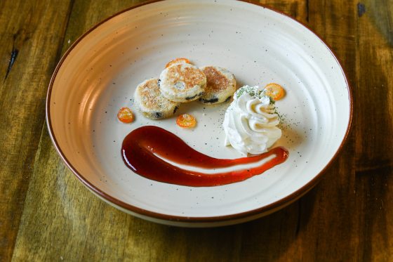 A white plate featuring tea cakes with a red splash of puree.