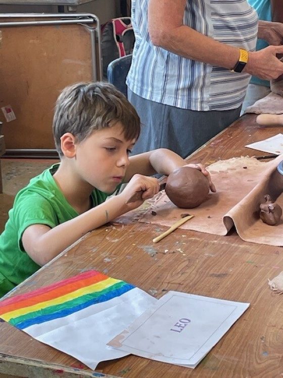 A young child working with a clay ball at a wood table.