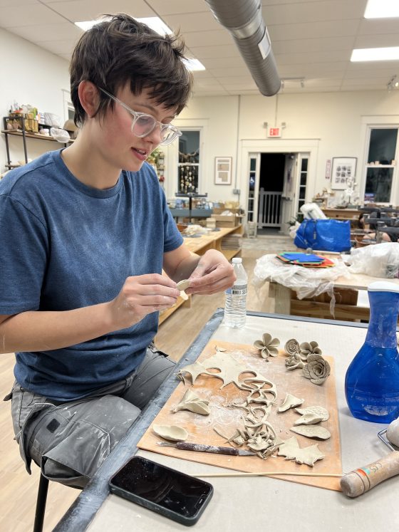 A person working on a clay ornament in a workshop setting.