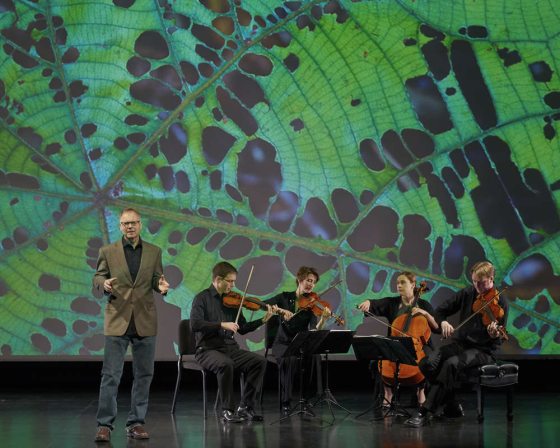 a small band performing on a stage with a green backdrop 